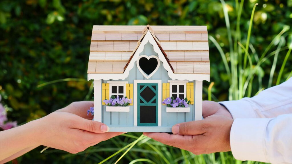 Guide to Deductible Rental Property Expenses (2025/26) Close-up of hands holding a detailed miniature house model, symbolizing goals of homeownership.